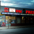 A little hard to see but there's a man talking on a payphone in front of a 99¢ Xpress Store.