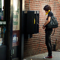 Man talking on one of two wall-mounted payphones